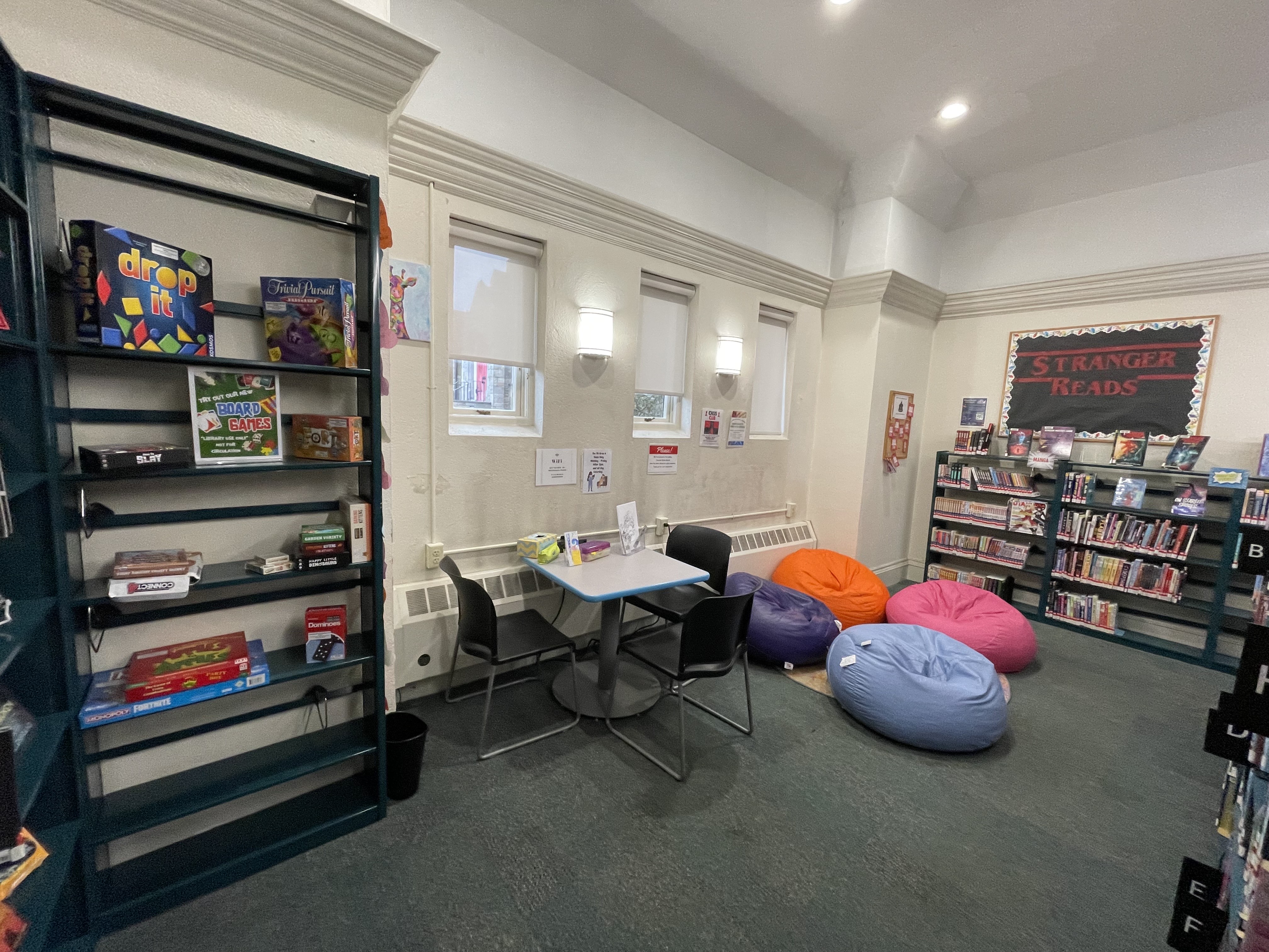 Teen Space with books board games and four bean bags book display table with three chairs