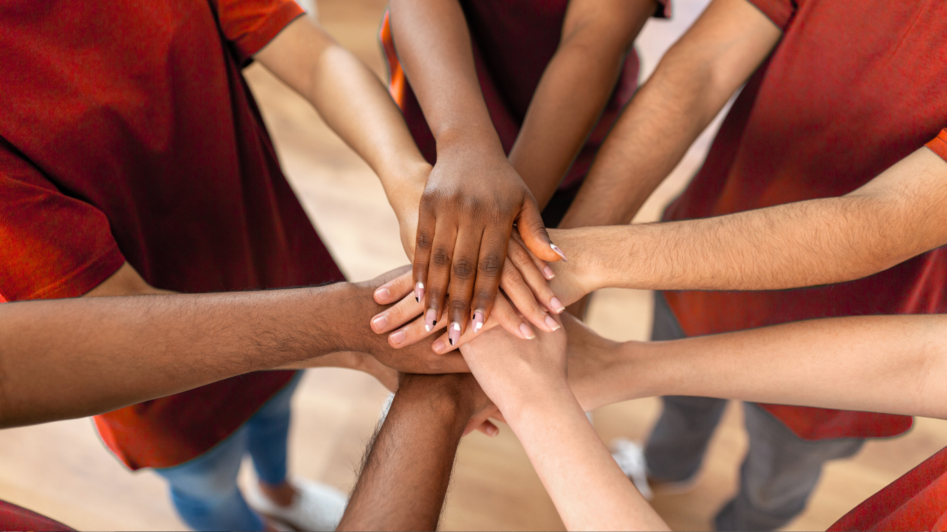 teen volunteer hands in a hand stack huddle circle
