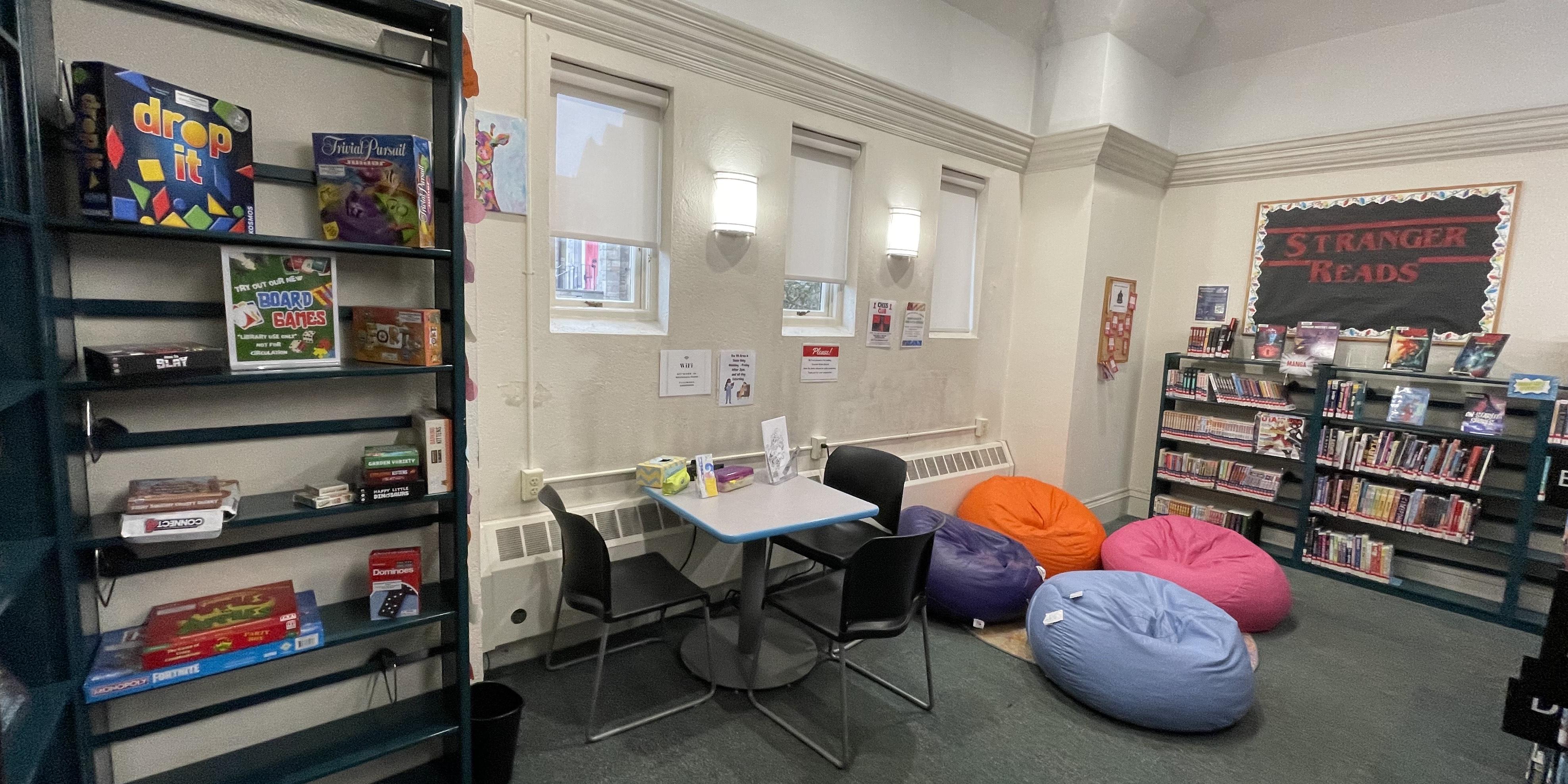 Teen Space with books board games and four bean bags book display table with three chairs