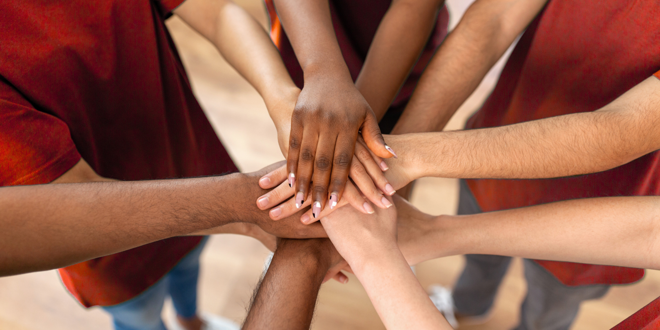 teen volunteer hands in a hand stack huddle circle